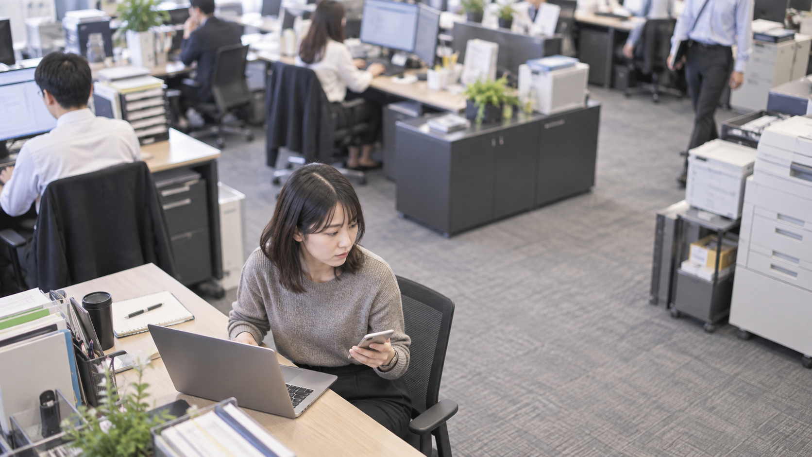 20代後半の日本人女性が自席でのスマートフォン併用をしている場面