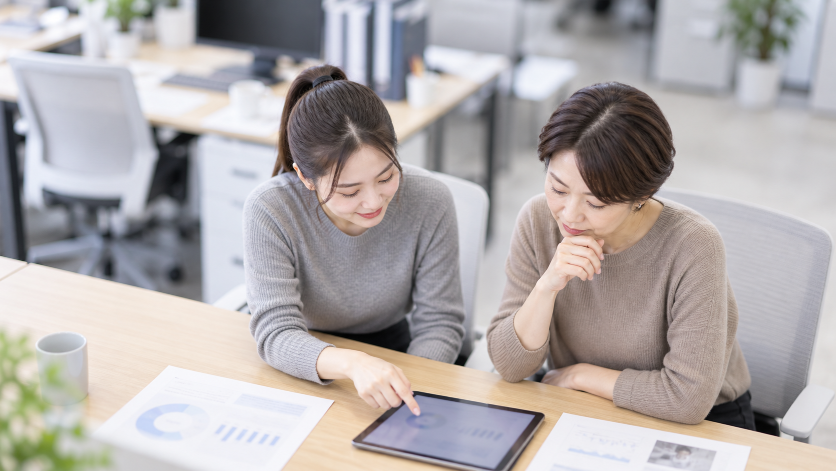 20代後半の日本人女性が会議でのタブレット共有をしている場面