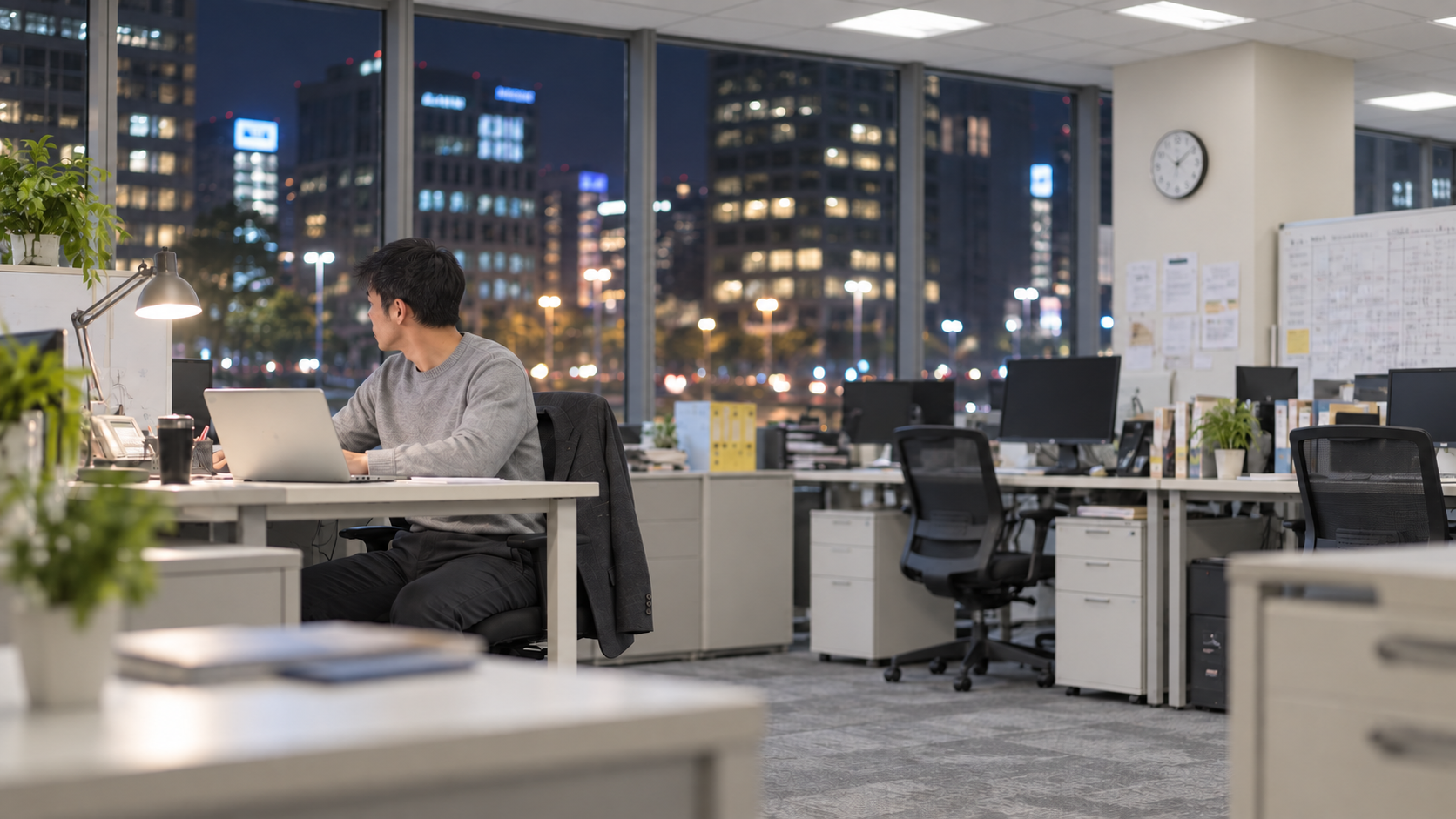 30代前半の日本人男性が夜のオフィスでの作業をしている場面