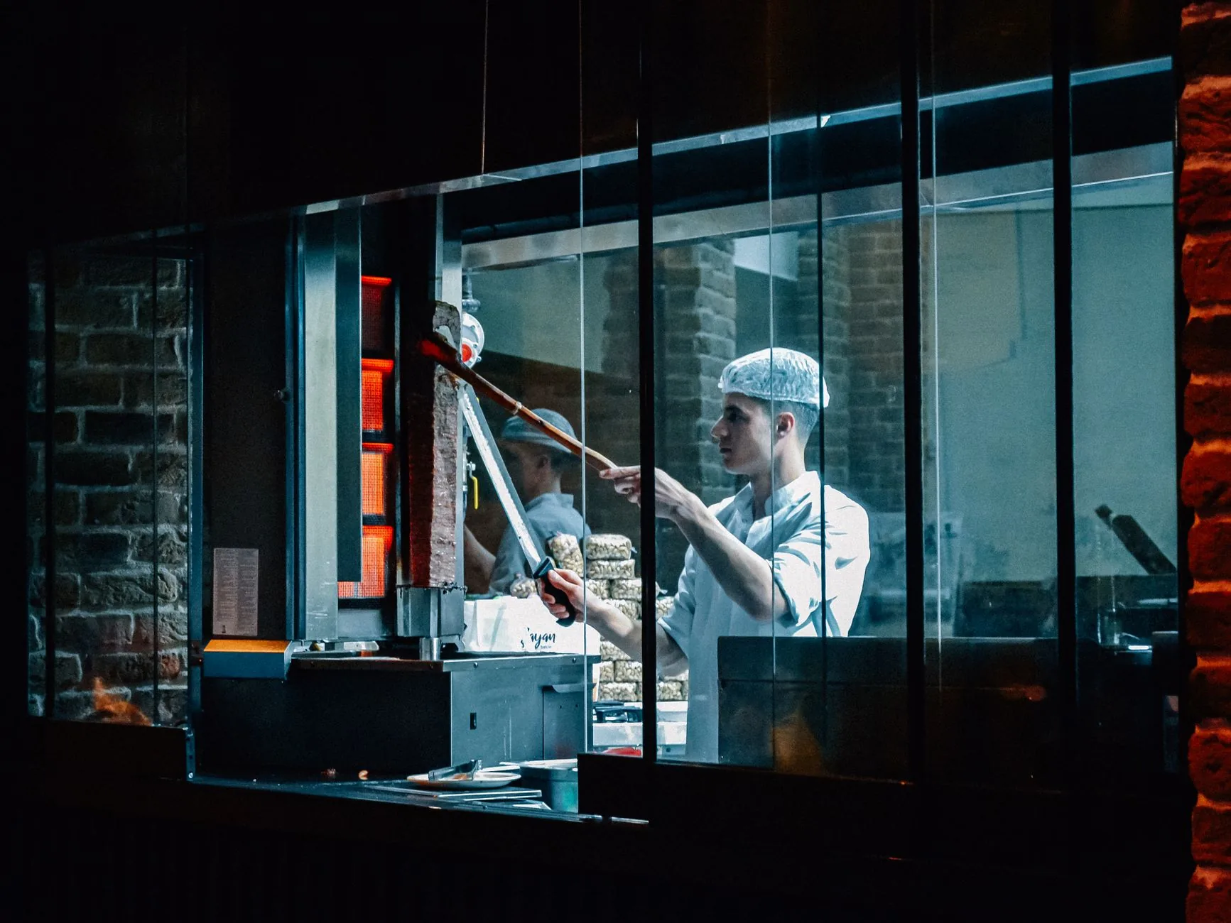 Chef skillfully prepares rotisserie meat in a modern restaurant kitchen.