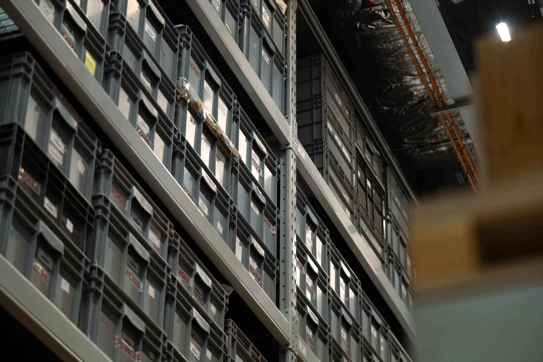 Perspective view of industrial shelves filled with organized plastic storage boxes in a warehouse.