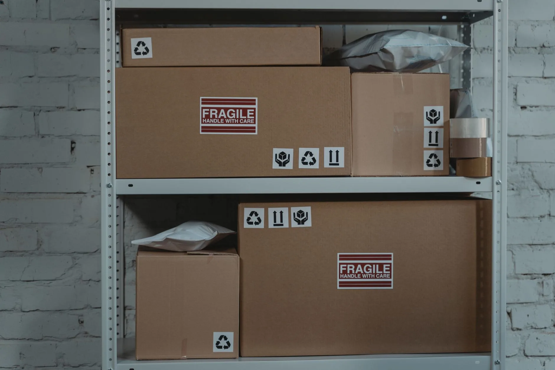 Cardboard boxes labeled 'Fragile' stacked on metal shelving in a storage room.