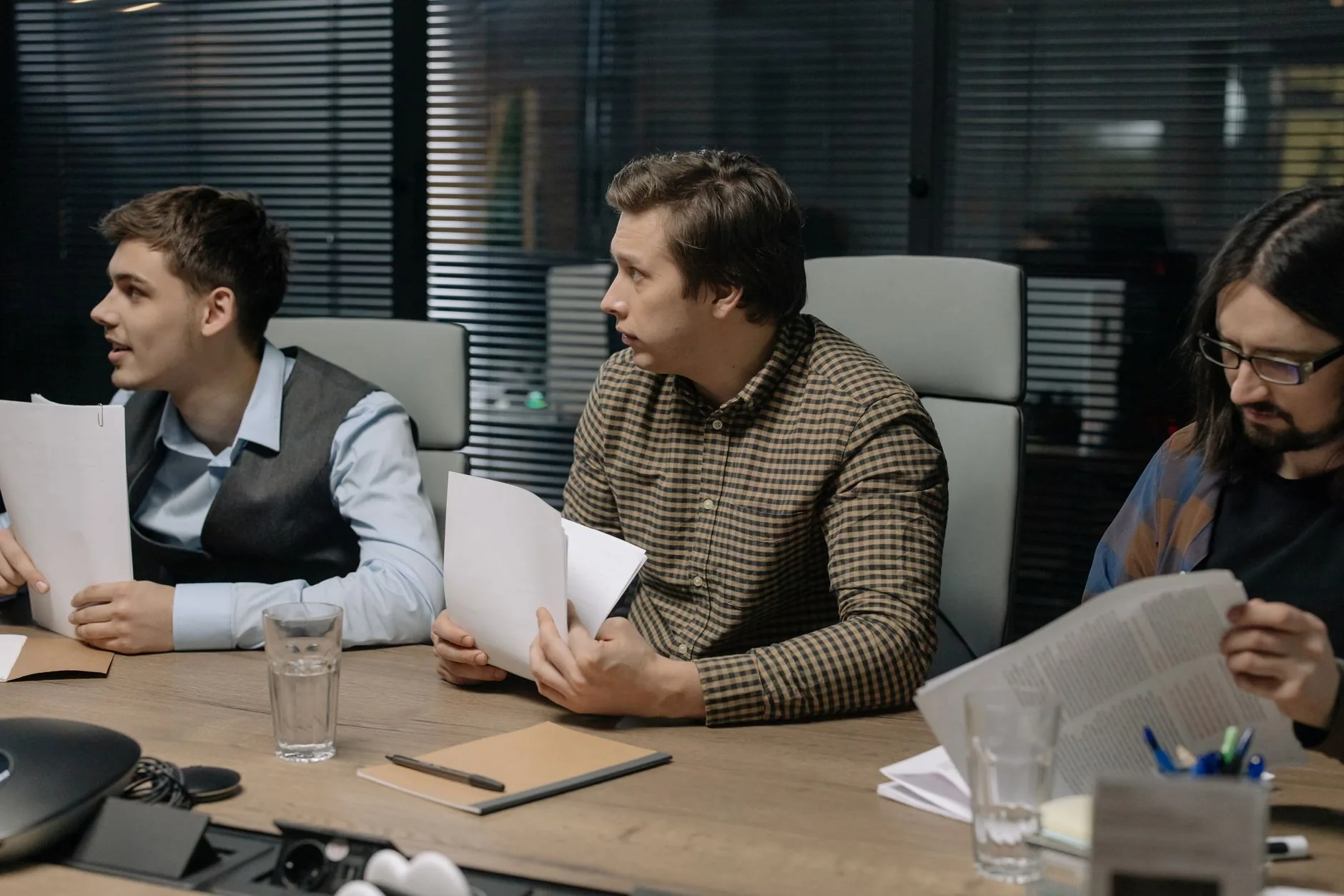 Three male colleagues engage in a business meeting discussing documents around a table.
