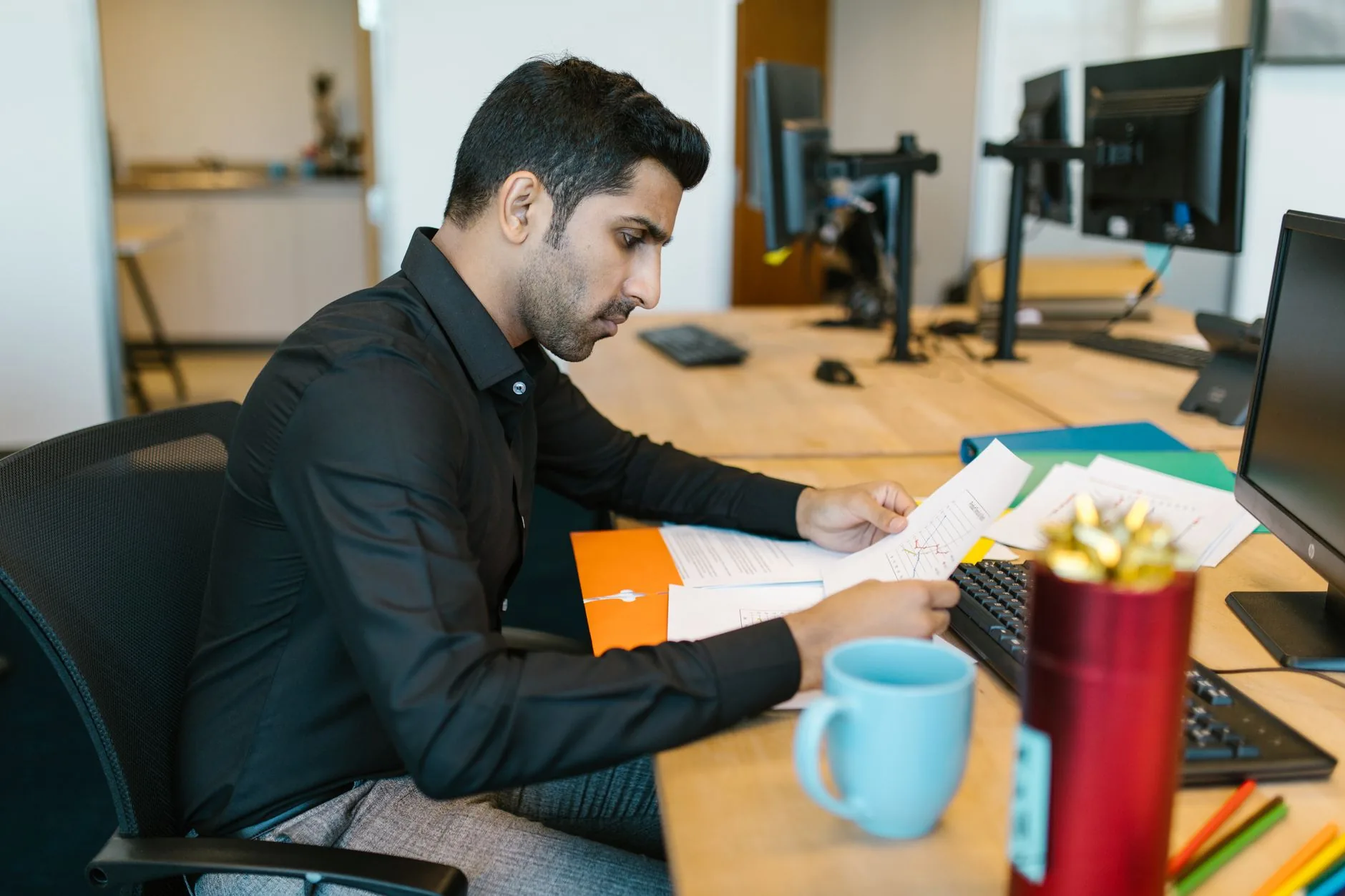 Professional male working at office desk reviewing important business documents.