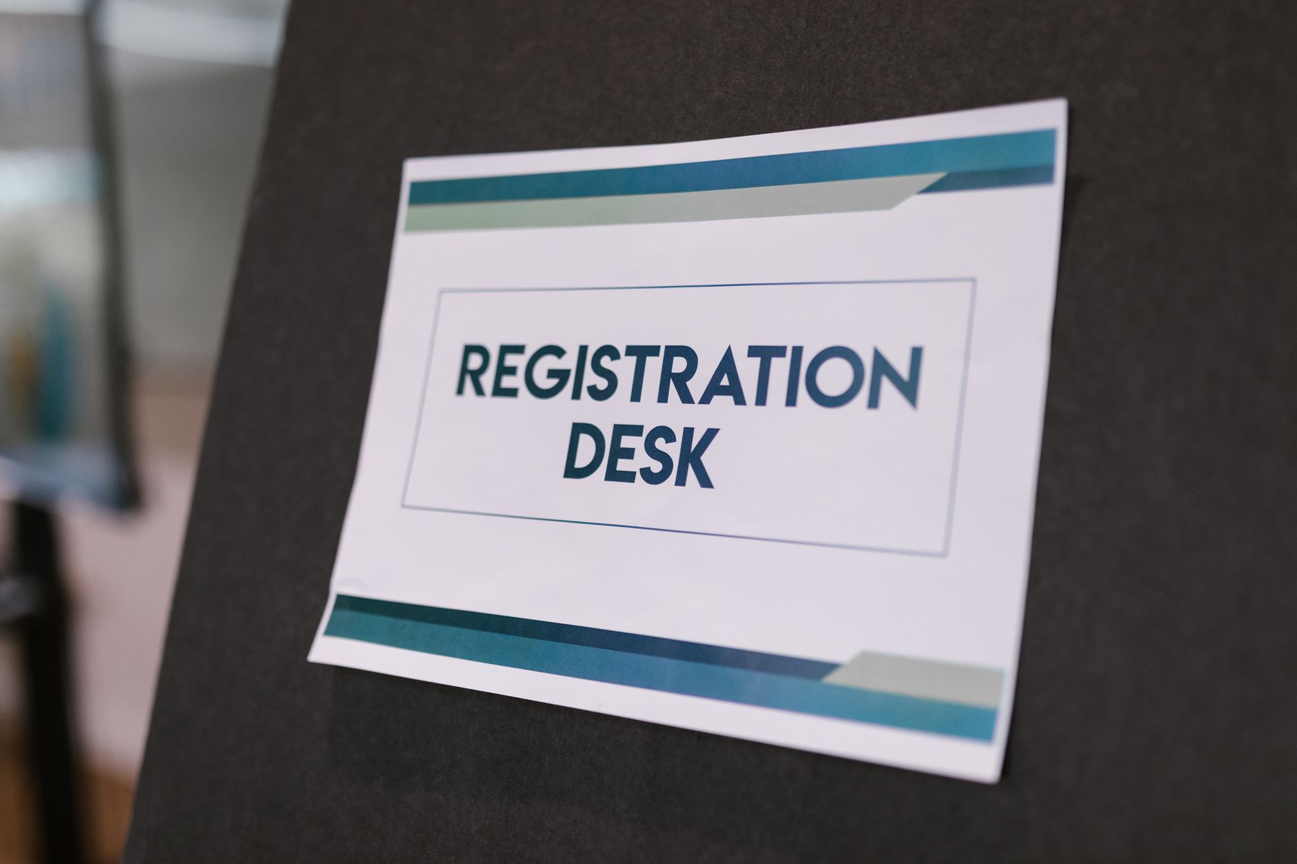 A close-up of a registration desk sign on a dark background.