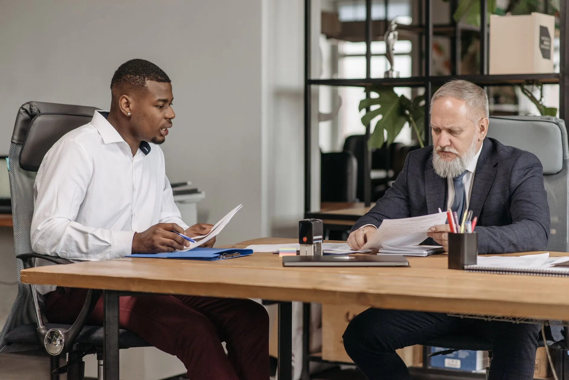 Two businessmen discussing documents during a meeting in a modern office.
