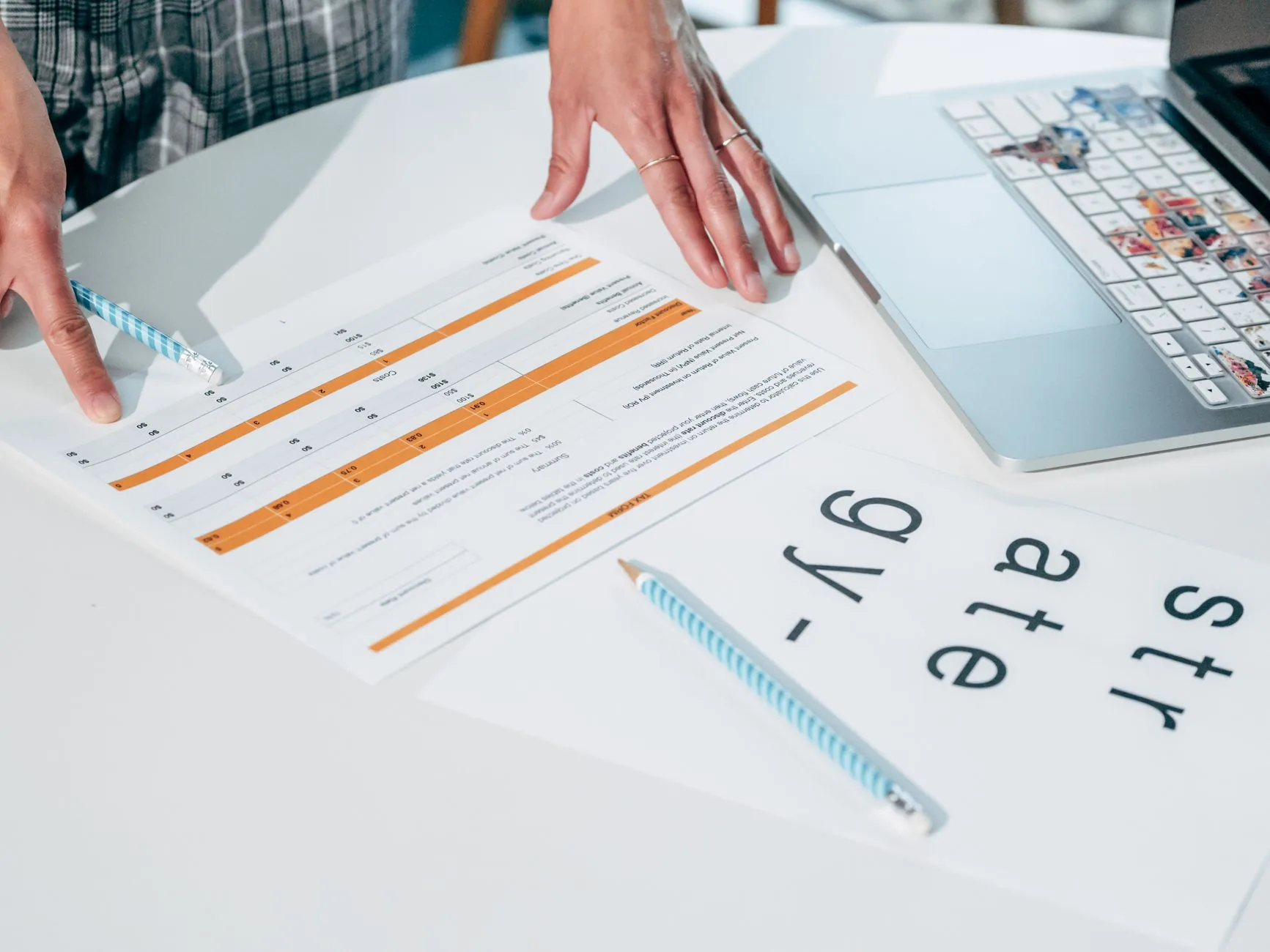 Close-up of hands reviewing business documents and strategy papers on an office desk.