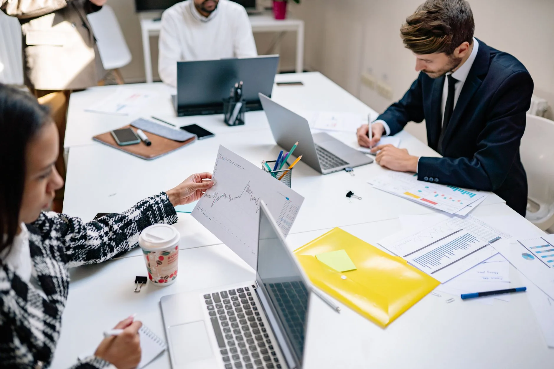 Professionals collaborating in a modern office with laptops and documents, focusing on teamwork.