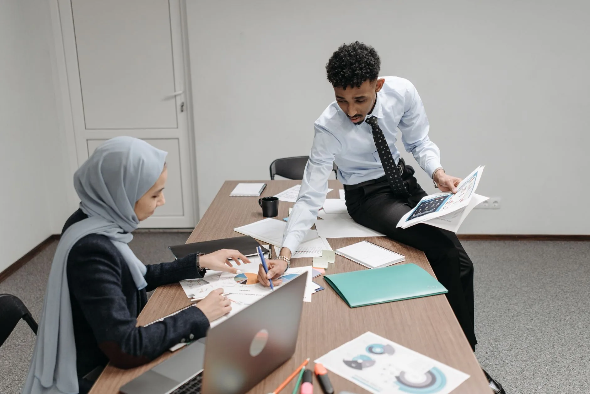 Colleagues discussing documents in a modern office meeting room.