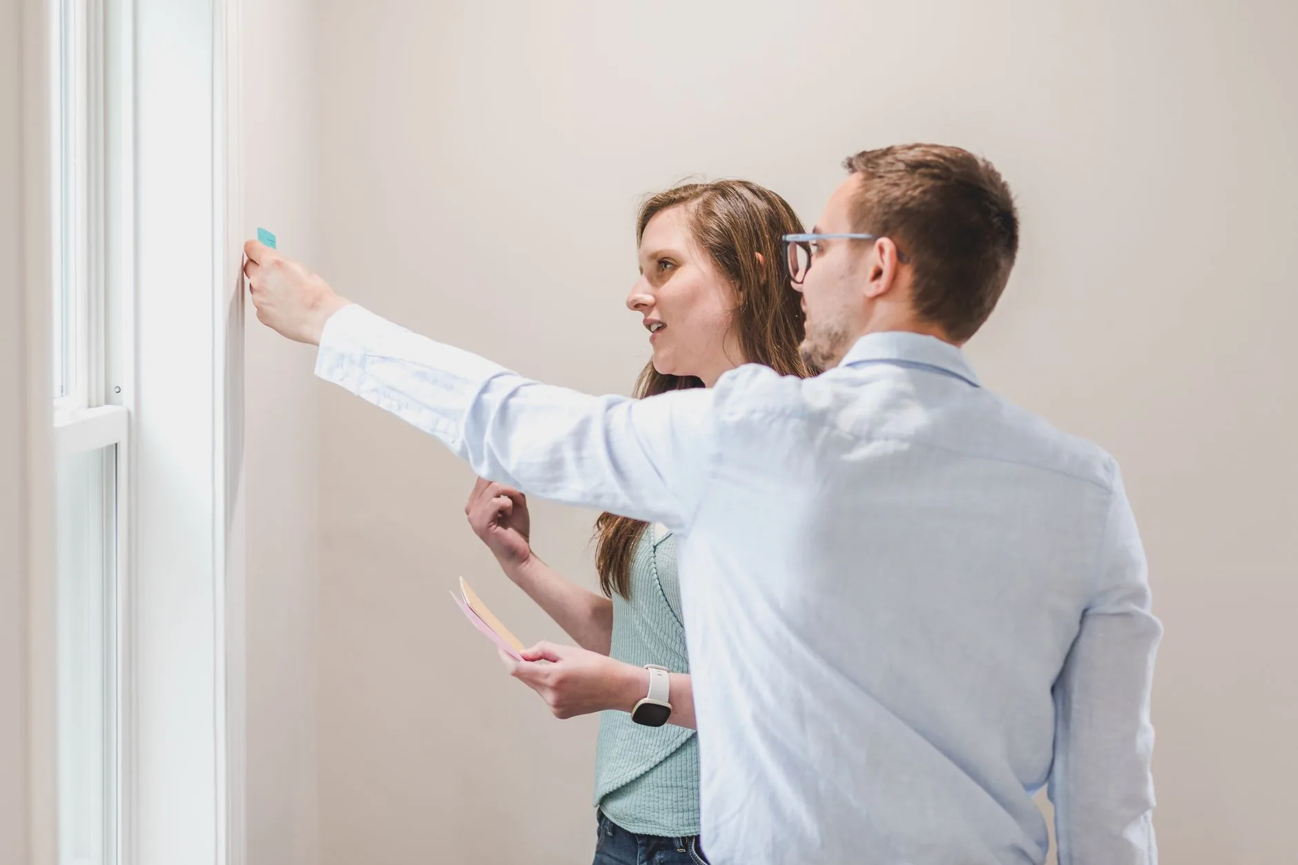 Young professionals collaborating and brainstorming with sticky notes on a wall.