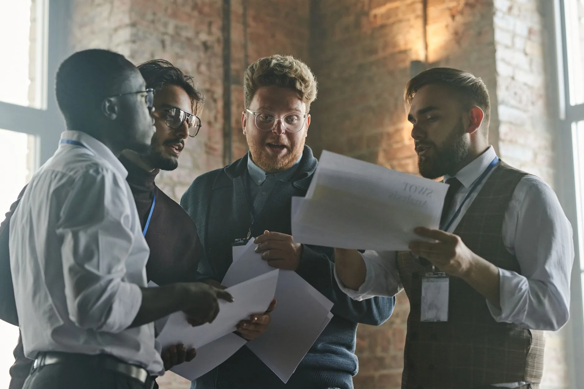 Group of colleagues discussing documents in an industrial-style office.