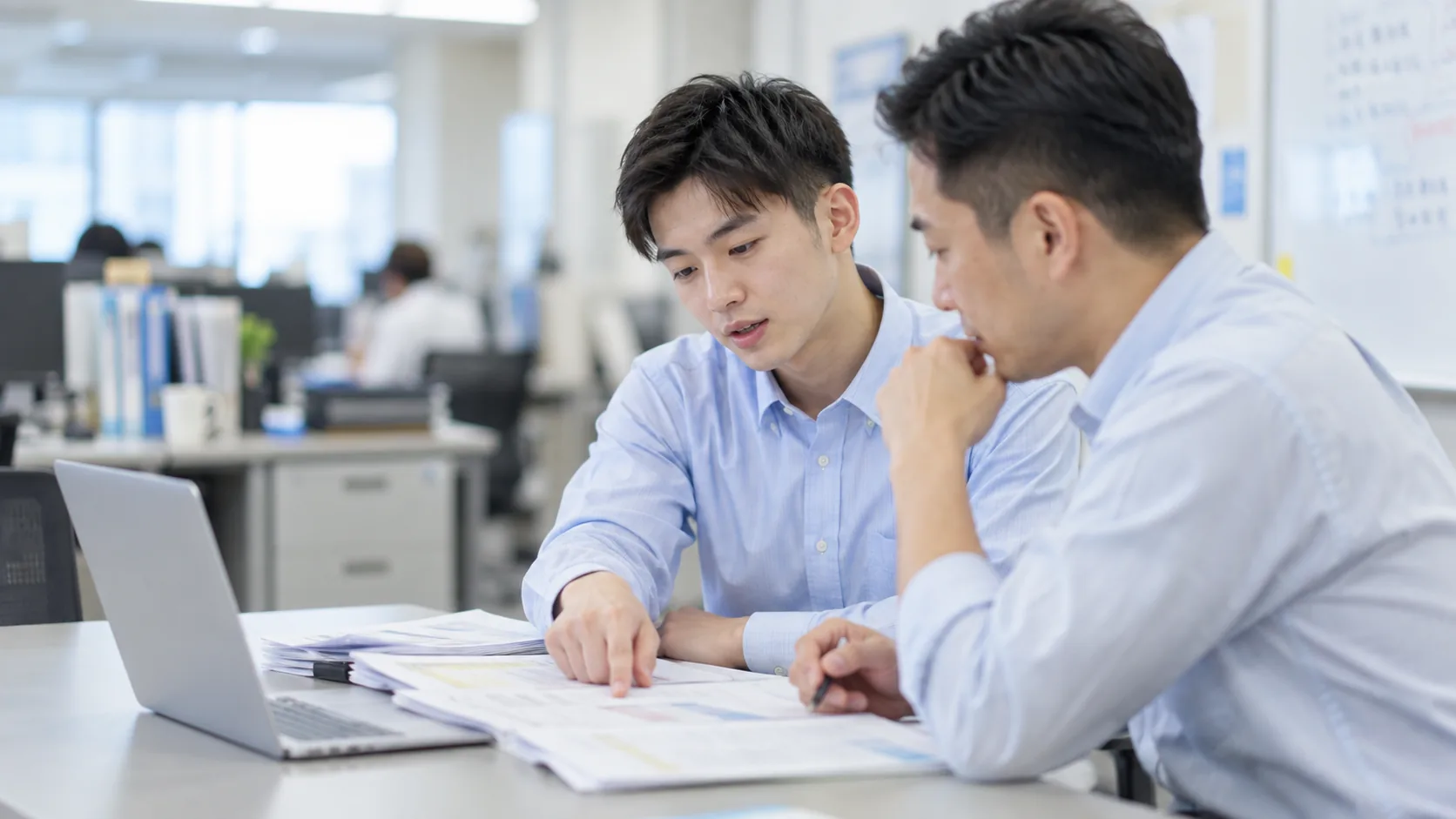 20代前半の日本人男性が小会議室での打ち合わせをしている場面