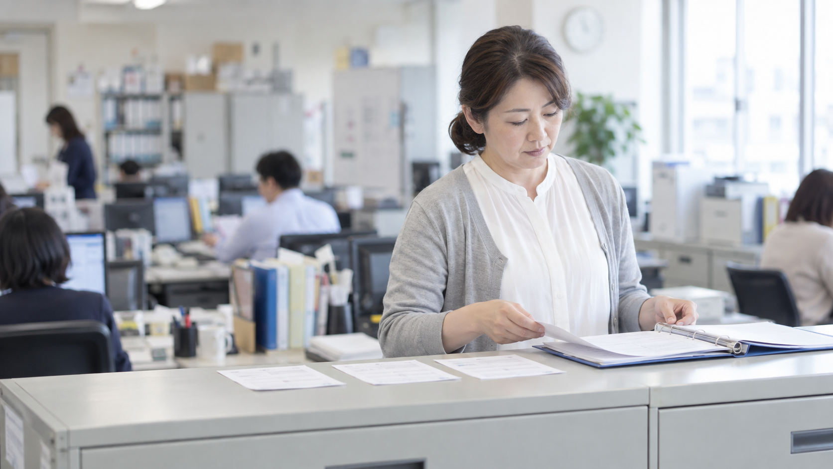 40代後半の日本人女性が発送控えのファイリングをしている場面