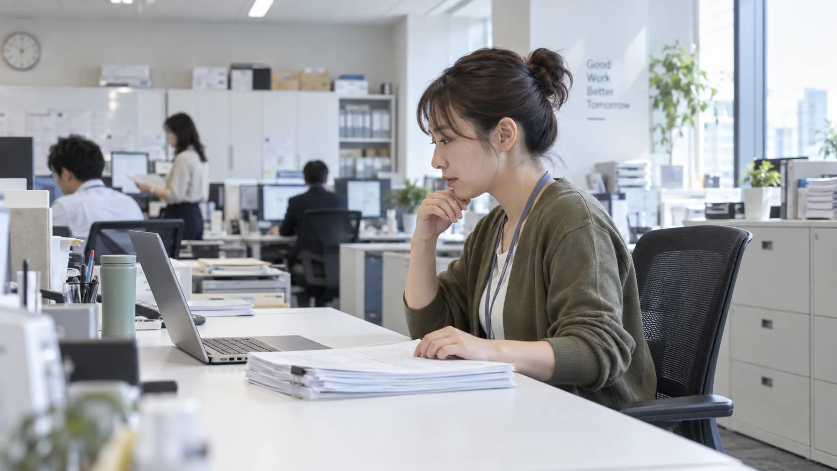 30代後半の日本人女性が自席での書類確認をしている場面