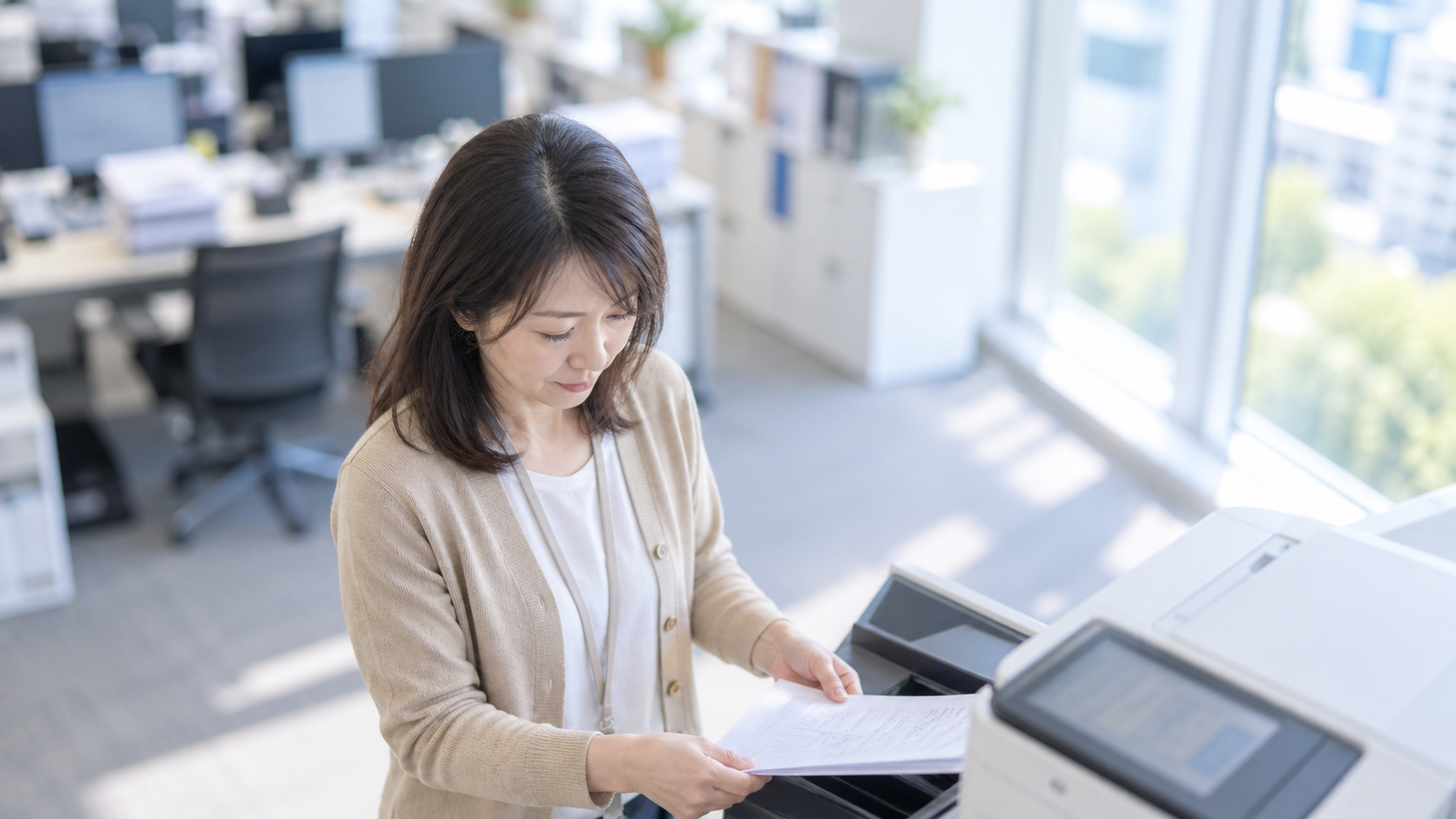 40代後半の日本人女性が複合機での出力をしている場面