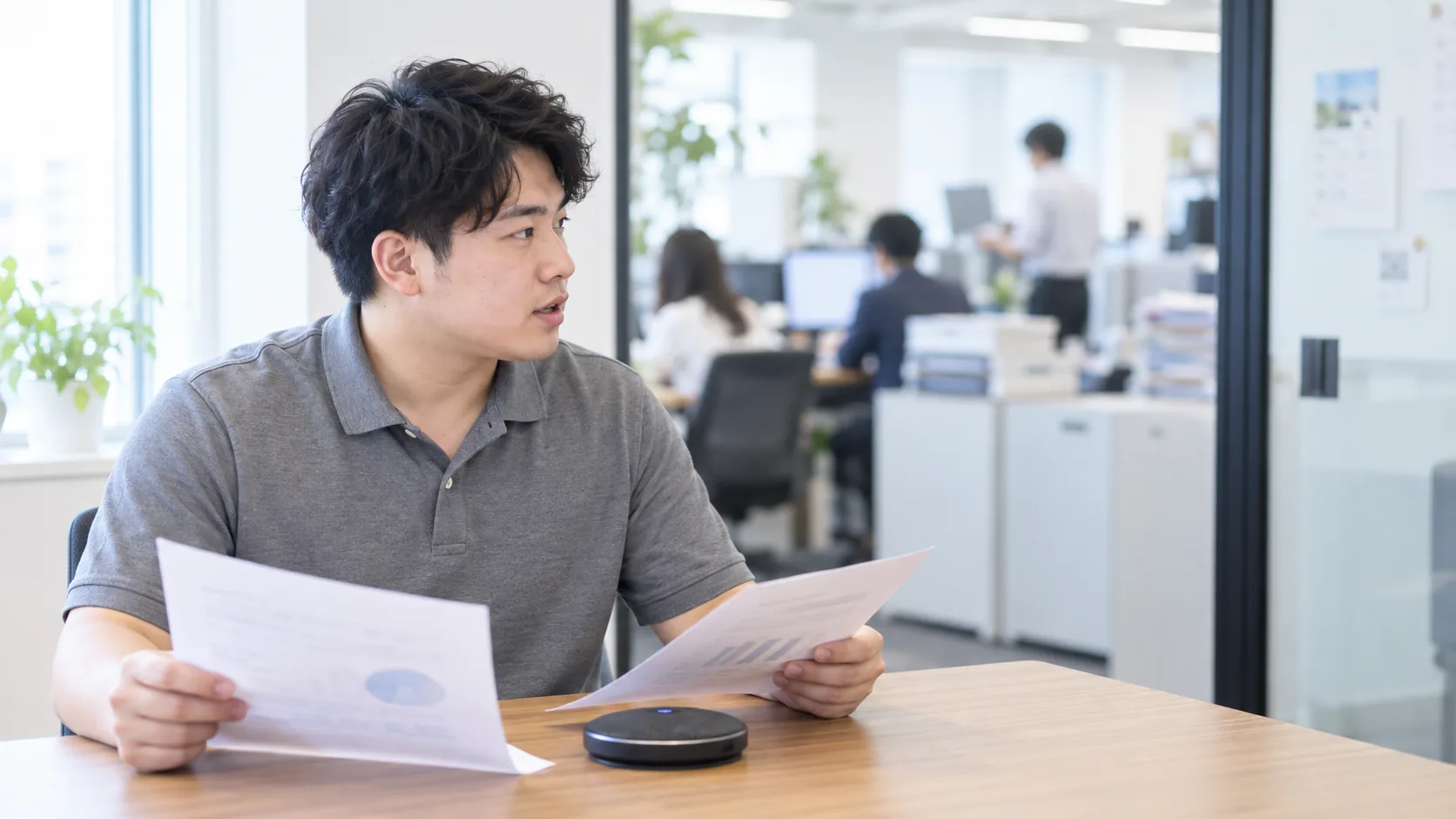 20代前半の日本人男性が電話会議室での通話をしている場面