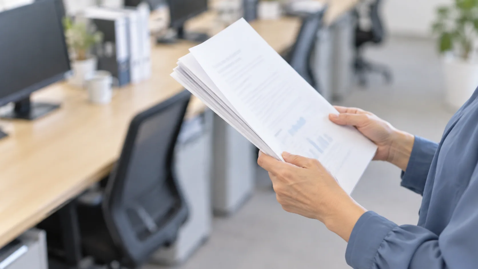 50代前半の日本人女性が窓際での書類確認をしている場面