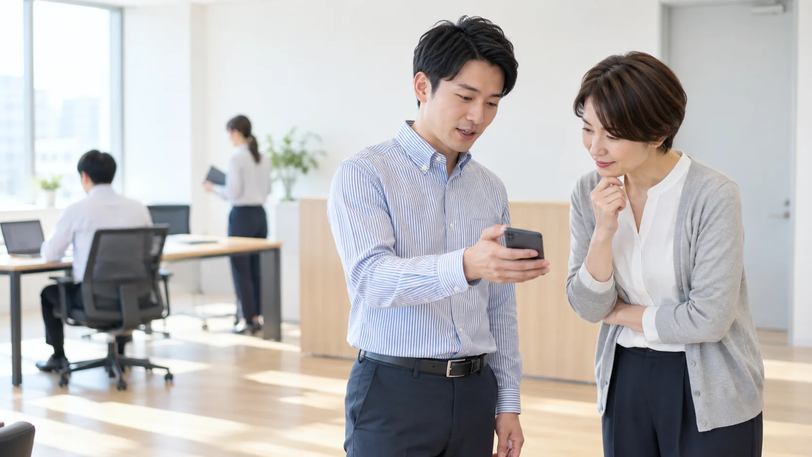 30代前半の日本人男性がスマートフォンの画面提示をしている場面