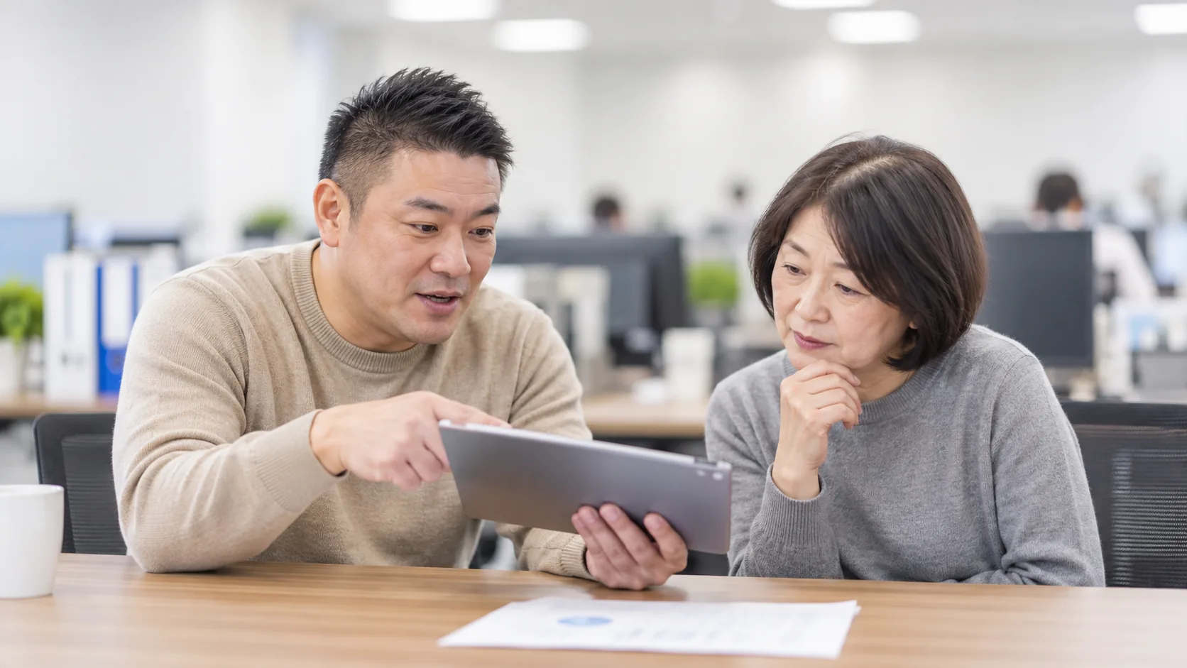 40代前半の日本人男性がタブレットでの提示をしている場面