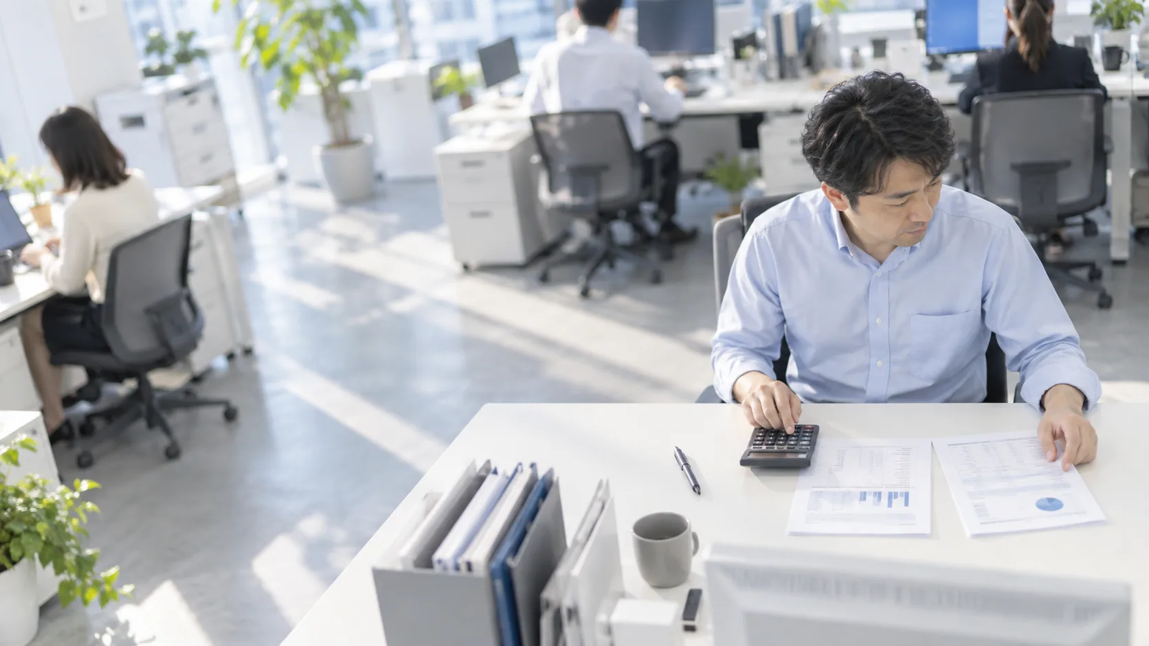 30代後半の日本人男性が電卓での入力をしている場面