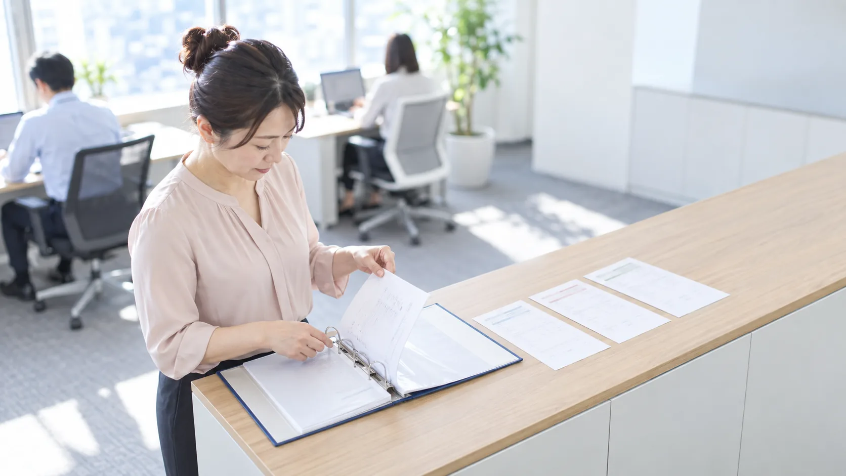 40代前半の日本人女性が発送控えのファイリングをしている場面