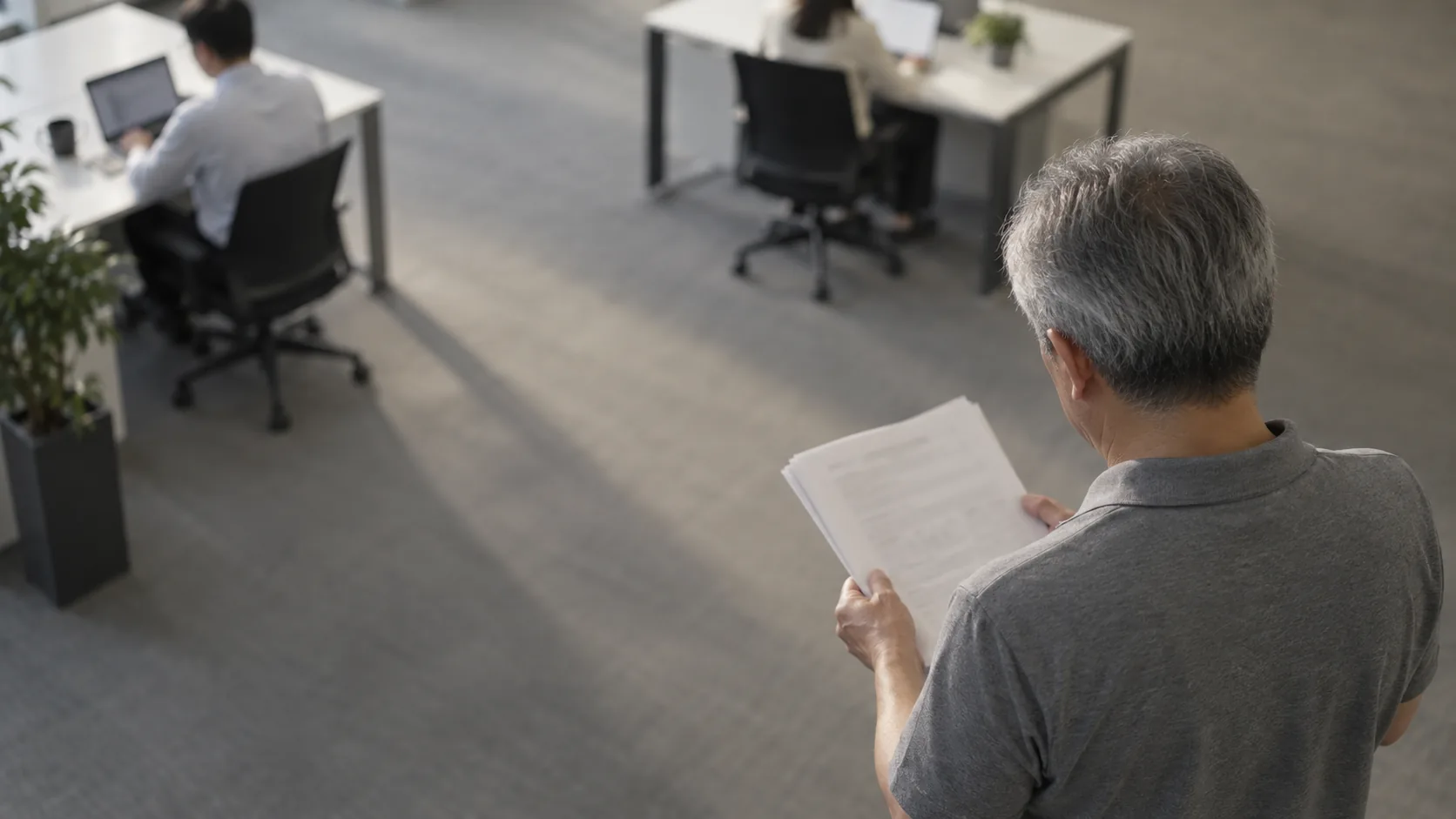 50代前半の日本人男性が窓際での書類確認をしている場面