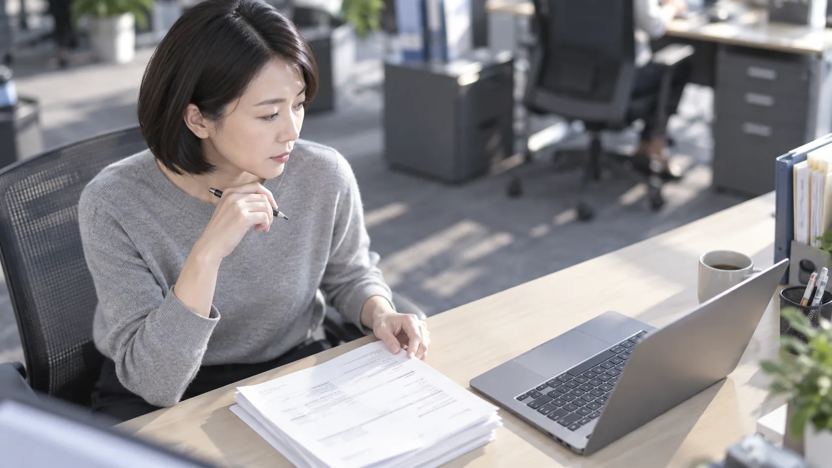 40代前半の日本人女性が自席での書類確認をしている場面