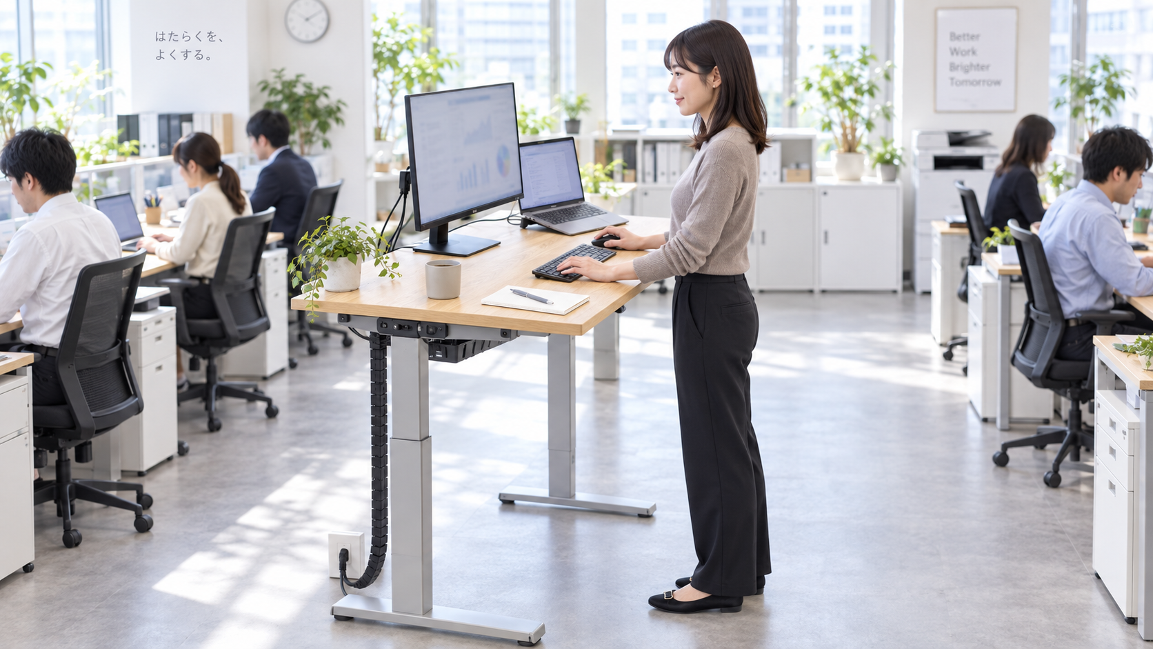 20代後半の日本人女性が昇降デスクでの立ち作業をしている場面