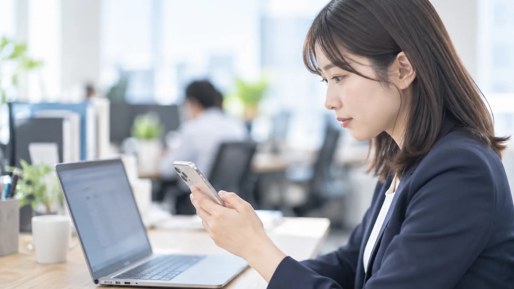 20代後半の日本人女性が自席でのスマートフォン併用をしている場面