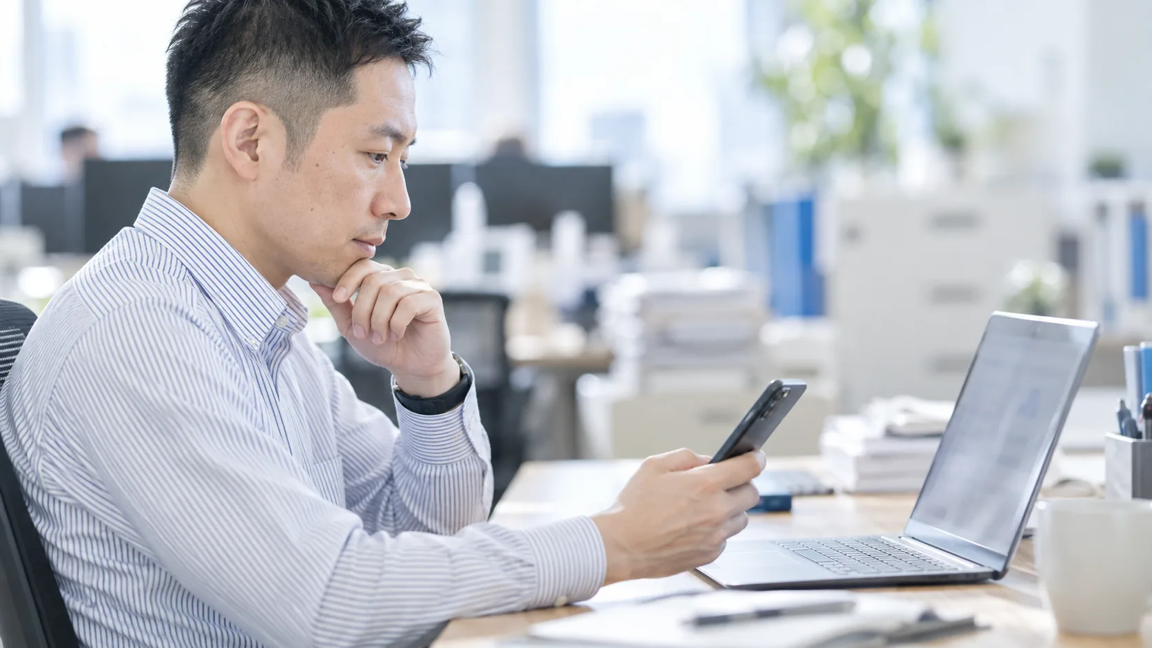 30代後半の日本人男性が自席でのスマートフォン併用をしている場面